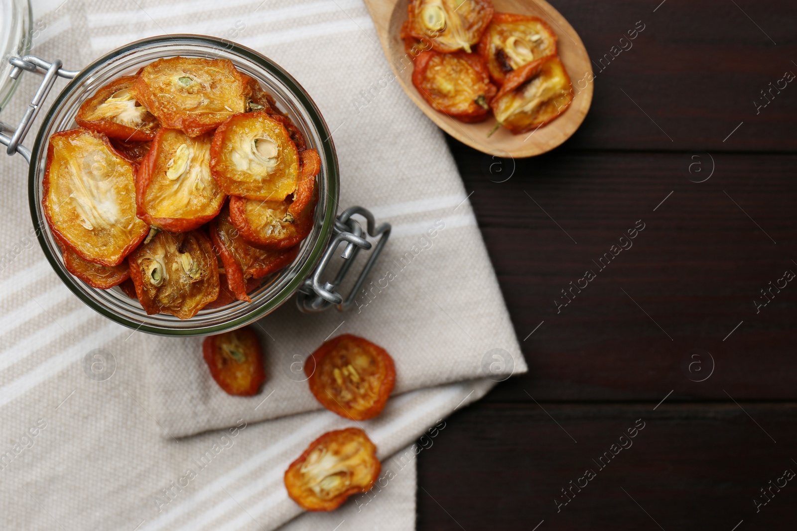 Photo of Jar and spoon with cut dried kumquat fruits on wooden table, flat lay. Space for text