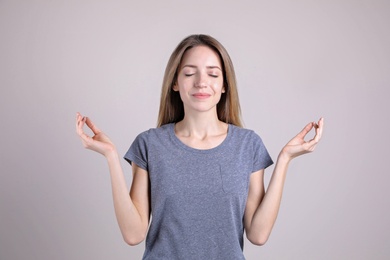 Photo of Young woman meditating on light background. Stress relief exercise