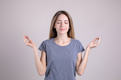 Young woman meditating on light background. Stress relief exercise