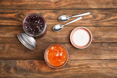 Two jars with tasty sweet jam on wooden table