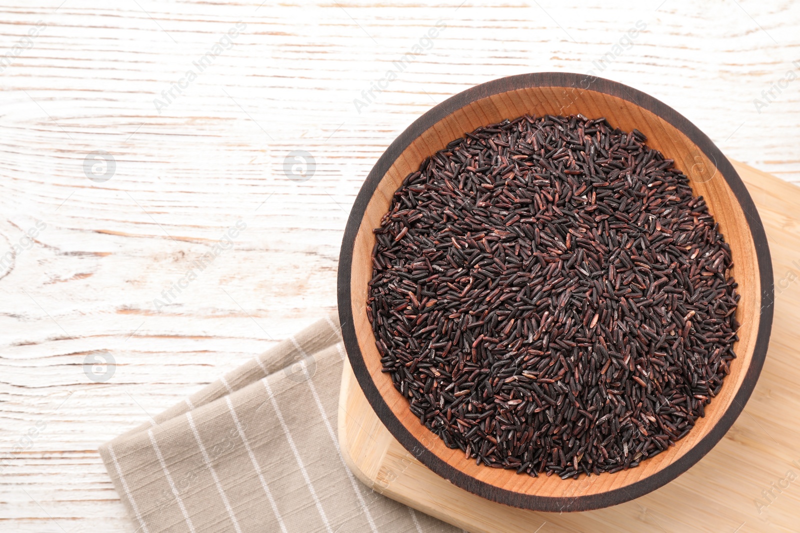 Photo of Brown rice on white wooden table, flat lay. Space for text