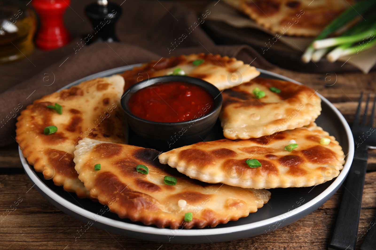 Photo of Delicious fried chebureki with ketchup served on wooden table