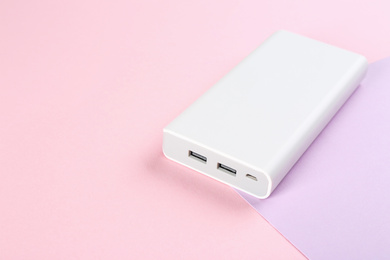 Photo of Modern external portable charger on color background. Space for text