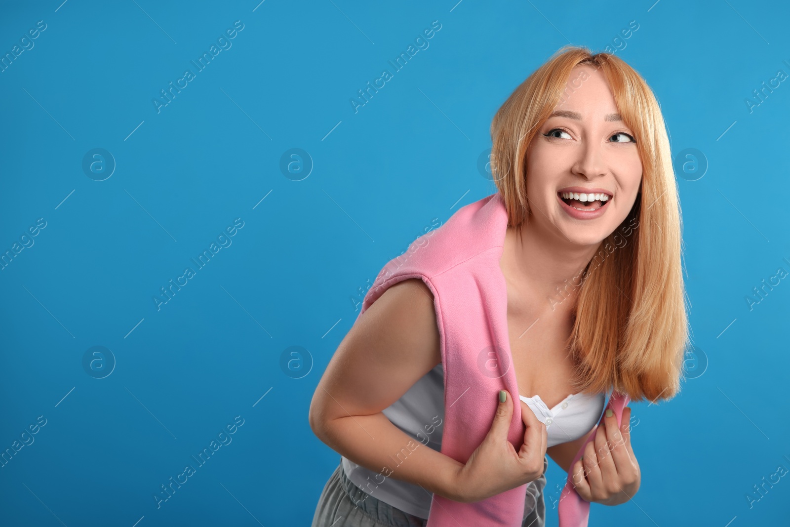 Photo of Beautiful young woman with blonde hair on blue background. Space for text