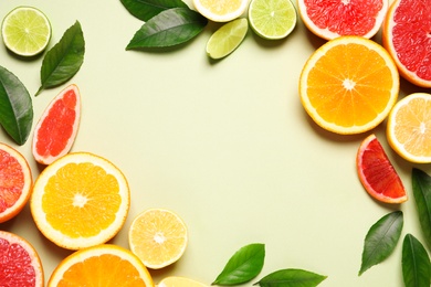 Photo of Frame of fresh juicy citrus fruits with green leaves on light background, flat lay. Space for text