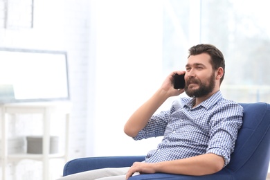 Portrait of confident mature man with mobile phone in armchair