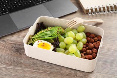 Photo of Healthy products high in vegetable fats near laptop on wooden table, closeup