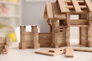 Photo of Wooden entry gate and building blocks on white table indoors, closeup. Children's toy