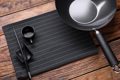 Empty iron wok, sauce bowl and chopsticks on wooden table