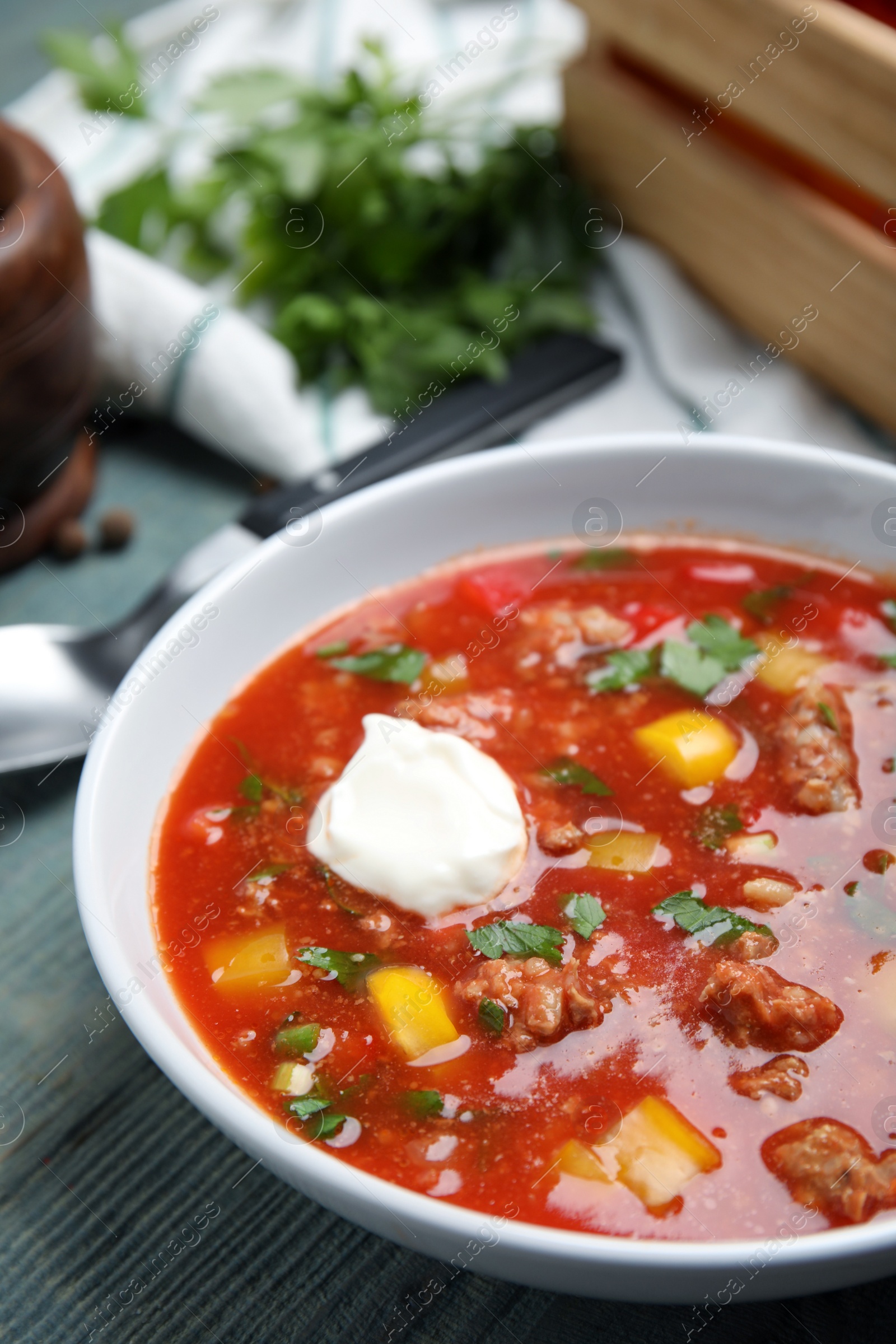 Photo of Bowl of delicious stuffed pepper soup on light blue wooden table, closeup