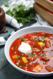 Bowl of delicious stuffed pepper soup on light blue wooden table, closeup