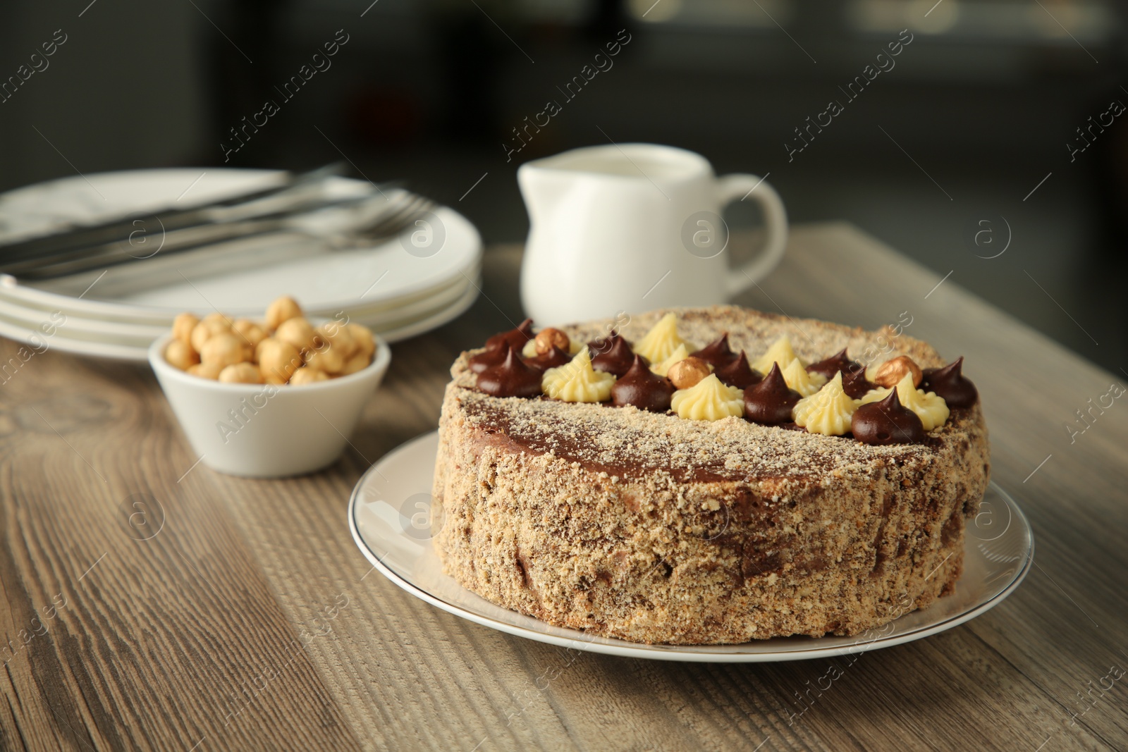 Photo of Delicious Kyiv Cake with cream and hazelnuts served on wooden table