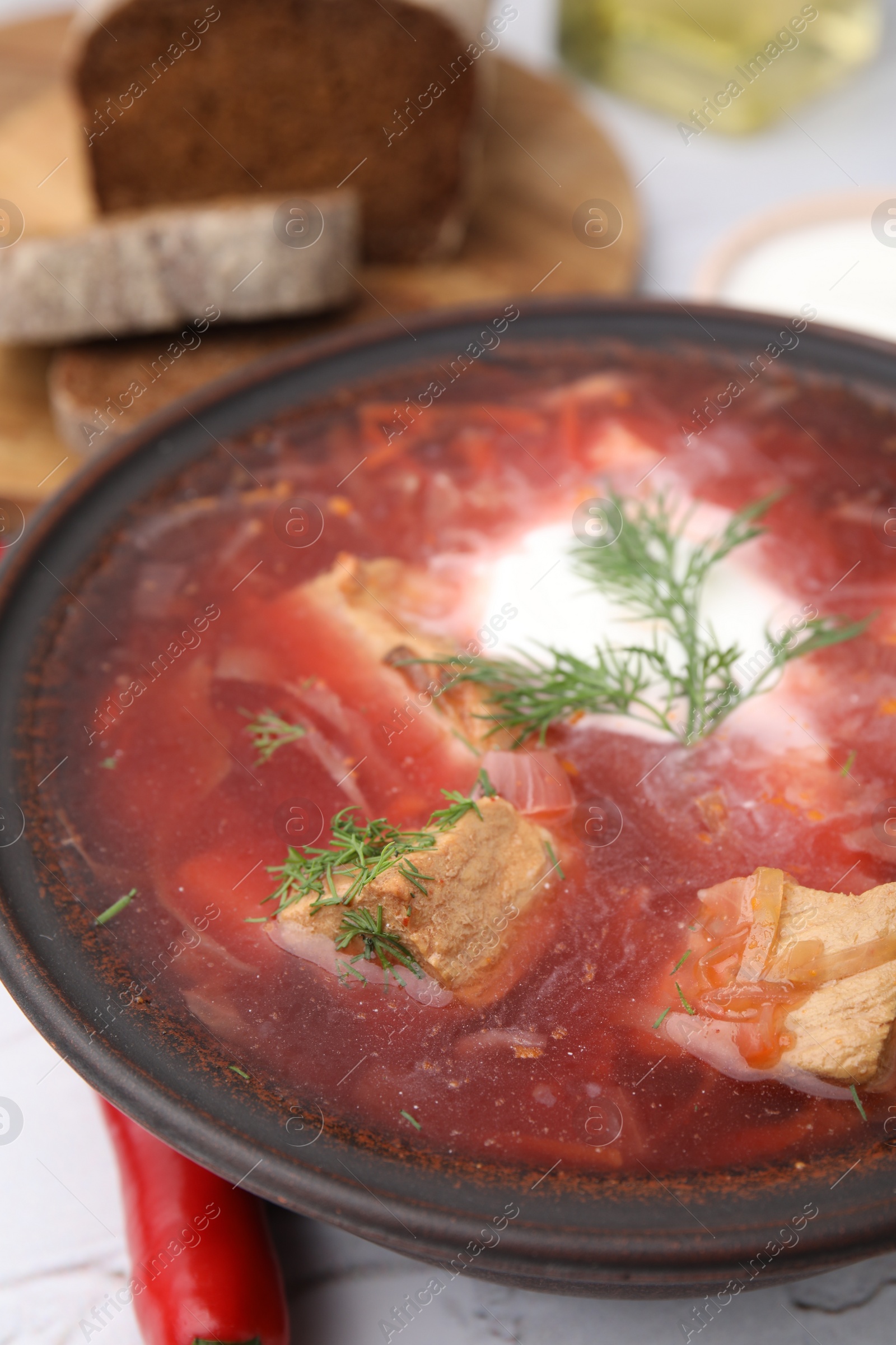 Photo of Tasty borscht with sour cream in bowl on table, closeup