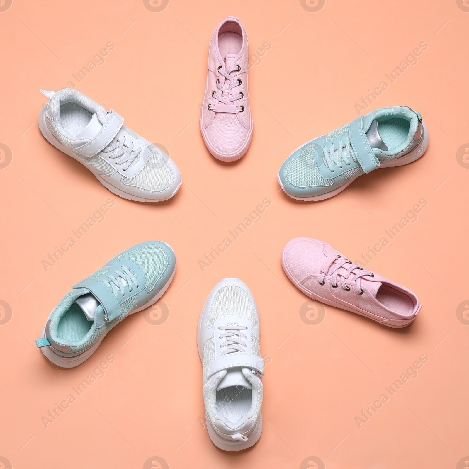 Photo of Flat lay composition with different stylish sports shoes on pale coral background