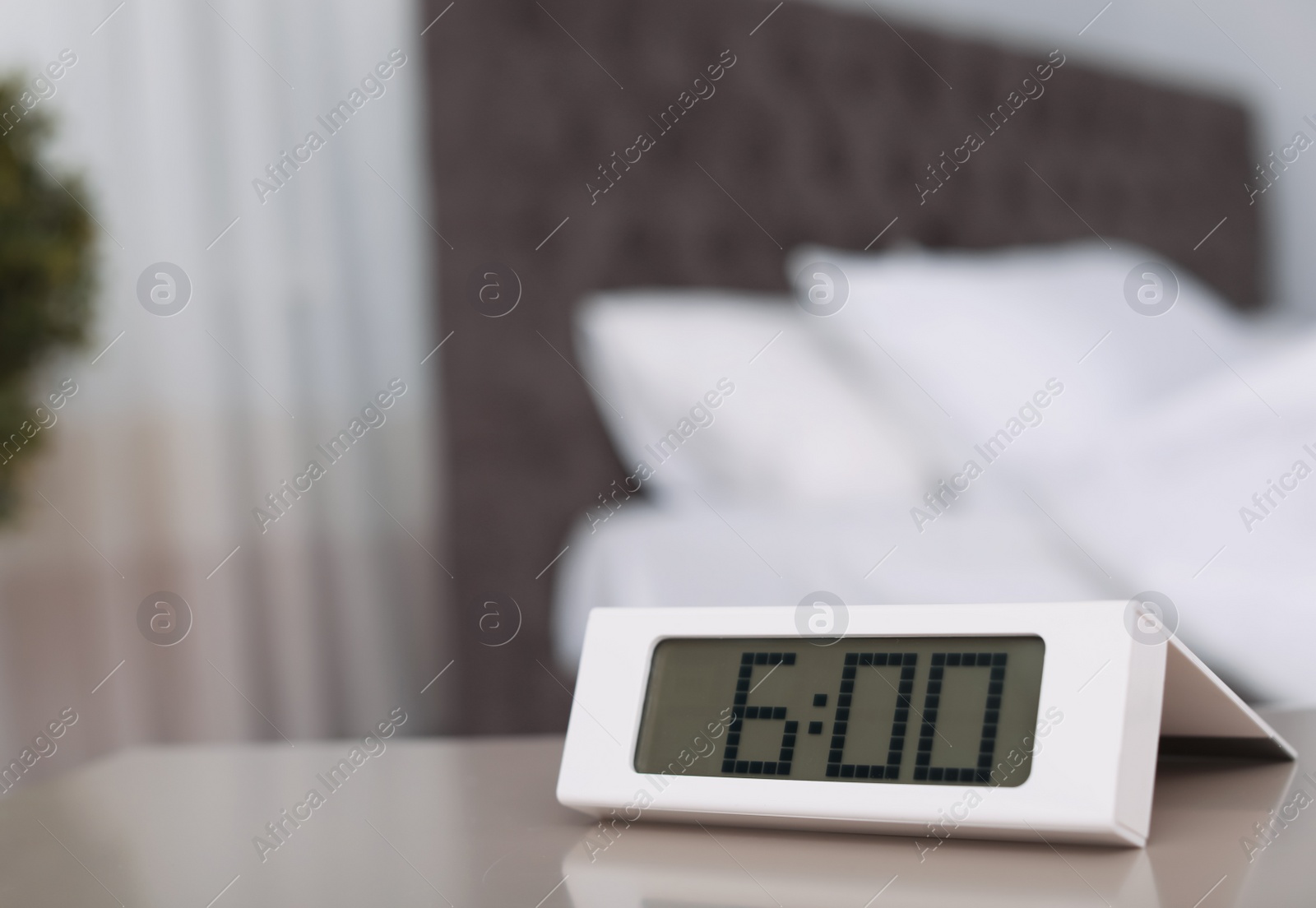 Photo of Digital alarm clock on table in bedroom. Time to wake up