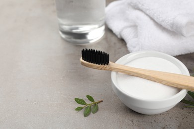 Photo of Bamboo toothbrush and bowl of baking soda on grey table. Space for text