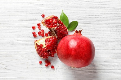 Flat lay composition with ripe pomegranates on white wooden background