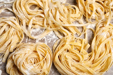 Uncooked noodles and flour on wooden table, above view