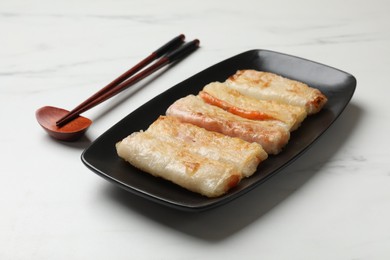 Photo of Delicious fried spring rolls and chopsticks on white table