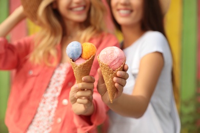 Photo of Young women with ice cream spending time together outdoors, focus on hands