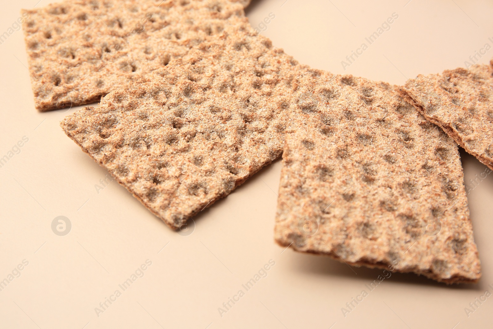 Photo of Fresh crunchy crispbreads on beige background, closeup