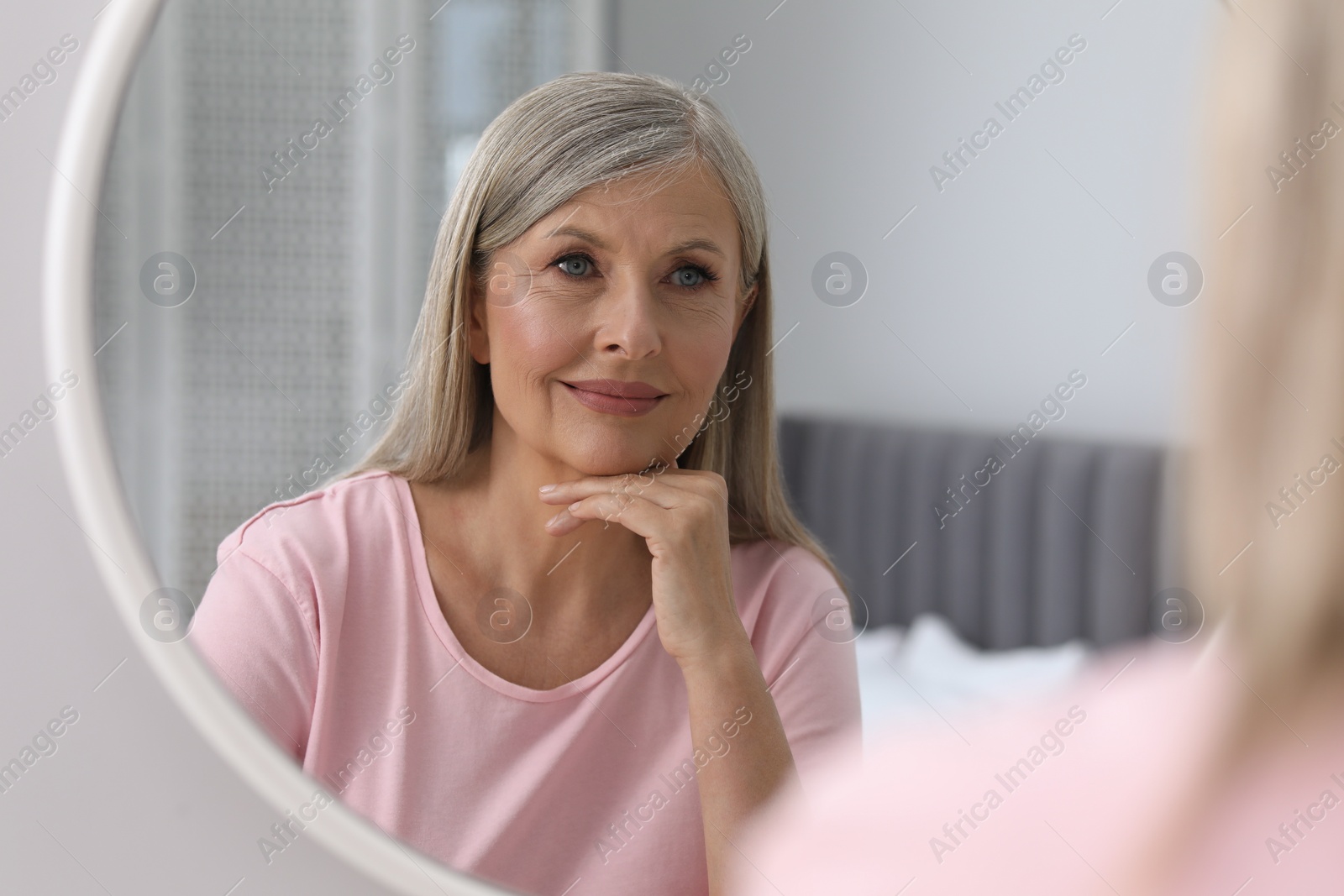 Photo of Beautiful senior woman near mirror in room