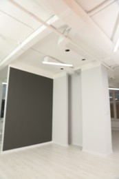 Photo of Blurred view of empty office room with color walls and modern lights on ceiling. Interior design