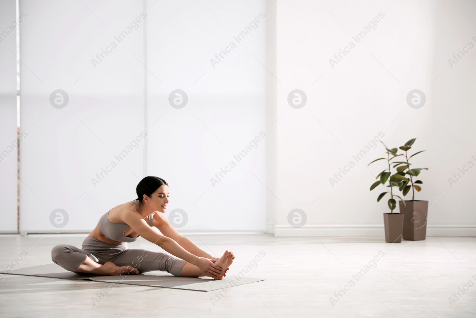 Photo of Young woman stretching leg in yoga studio. Janu Sirsasana pose variation