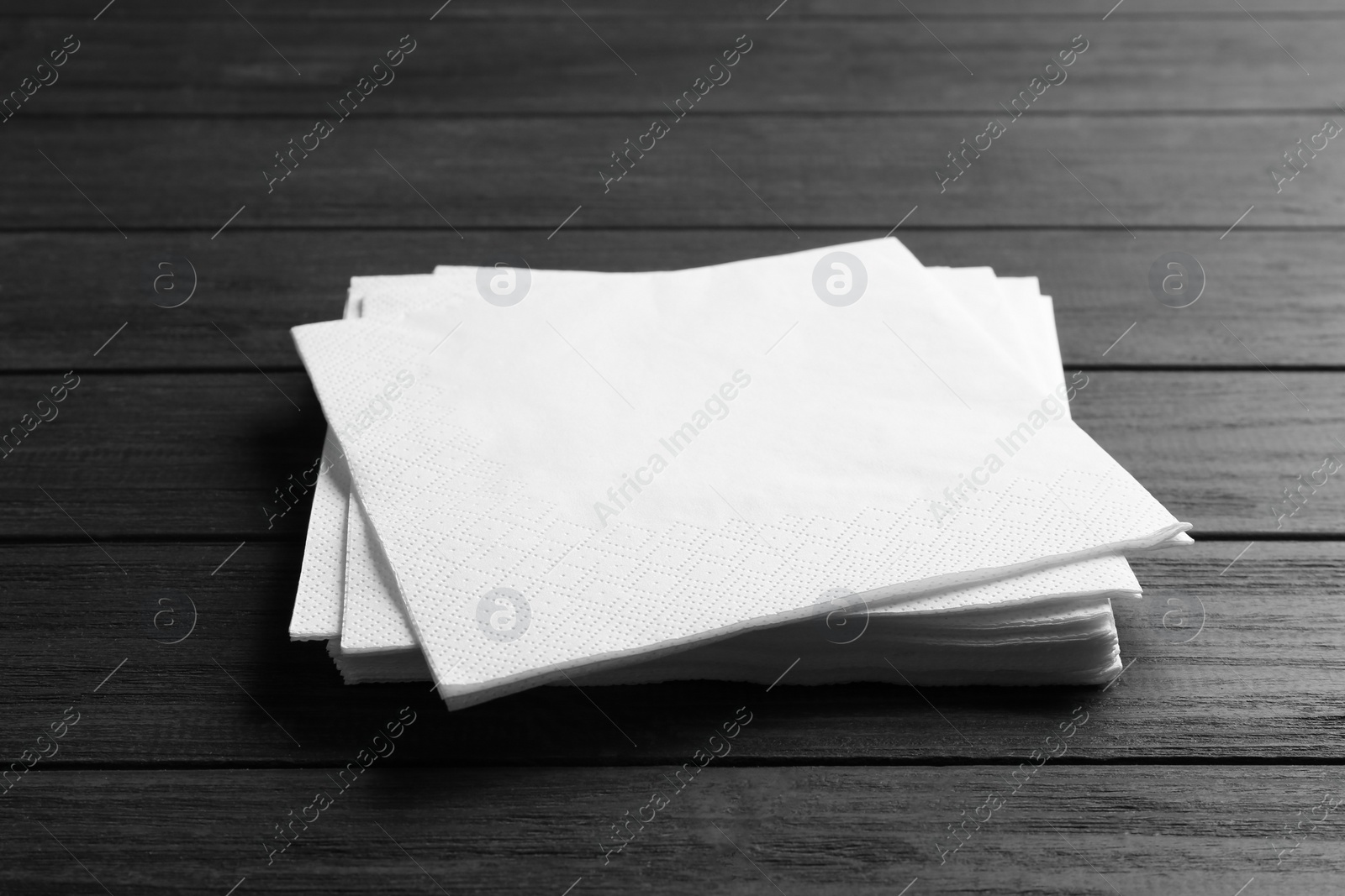 Photo of Stack of clean paper napkins on wooden background