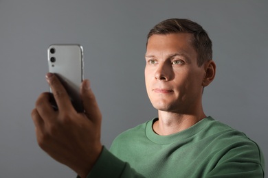 Photo of Man unlocking smartphone with facial scanner on grey background. Biometric verification