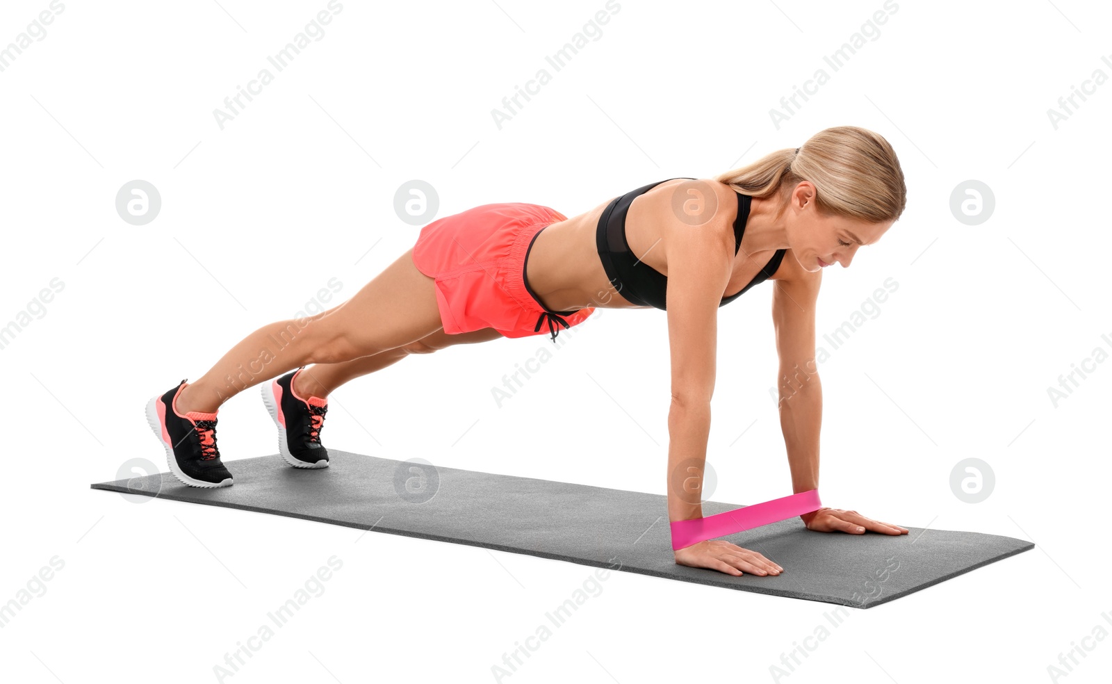 Photo of Woman exercising with elastic resistance band on fitness mat against white background