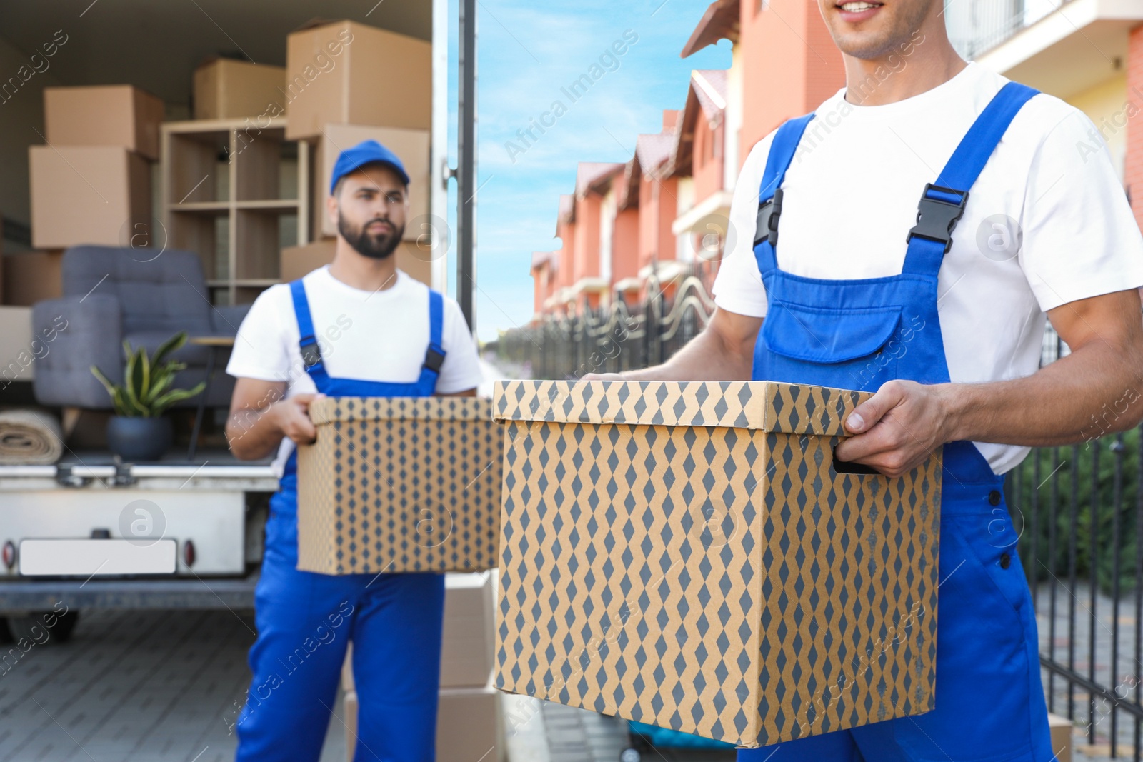 Photo of Workers unloading boxes from van outdoors. Moving service