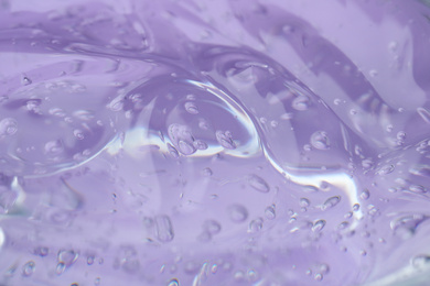 Photo of Pure transparent cosmetic gel on lilac background, closeup