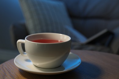 Photo of Cup of hot tea on wooden table at night