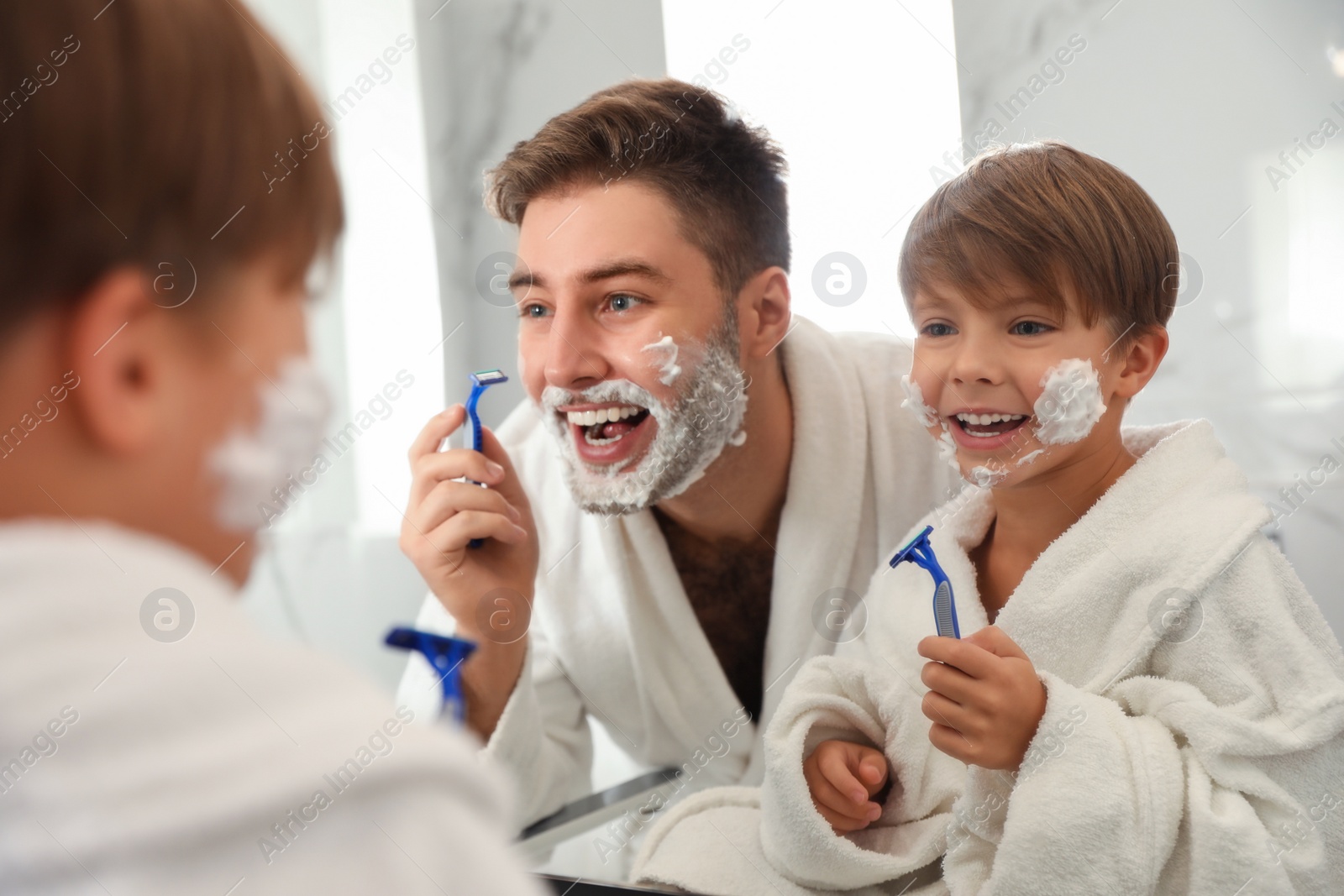 Photo of Dad shaving and son imitating him in bathroom