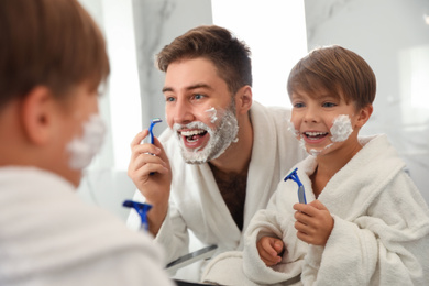 Dad shaving and son imitating him in bathroom