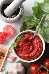 Photo of Tasty tomato paste in bowl and ingredients on table, flat lay