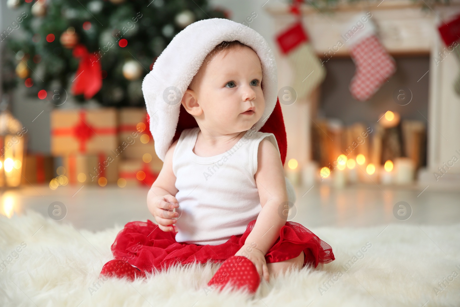 Photo of Cute baby in Santa hat on floor at home. Christmas celebration