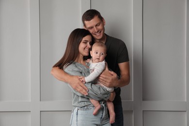 Photo of Happy family. Couple with their cute baby near light wall