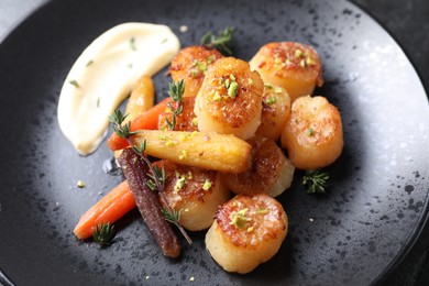 Photo of Delicious fried scallops with carrot and spices on dark gray plate, closeup