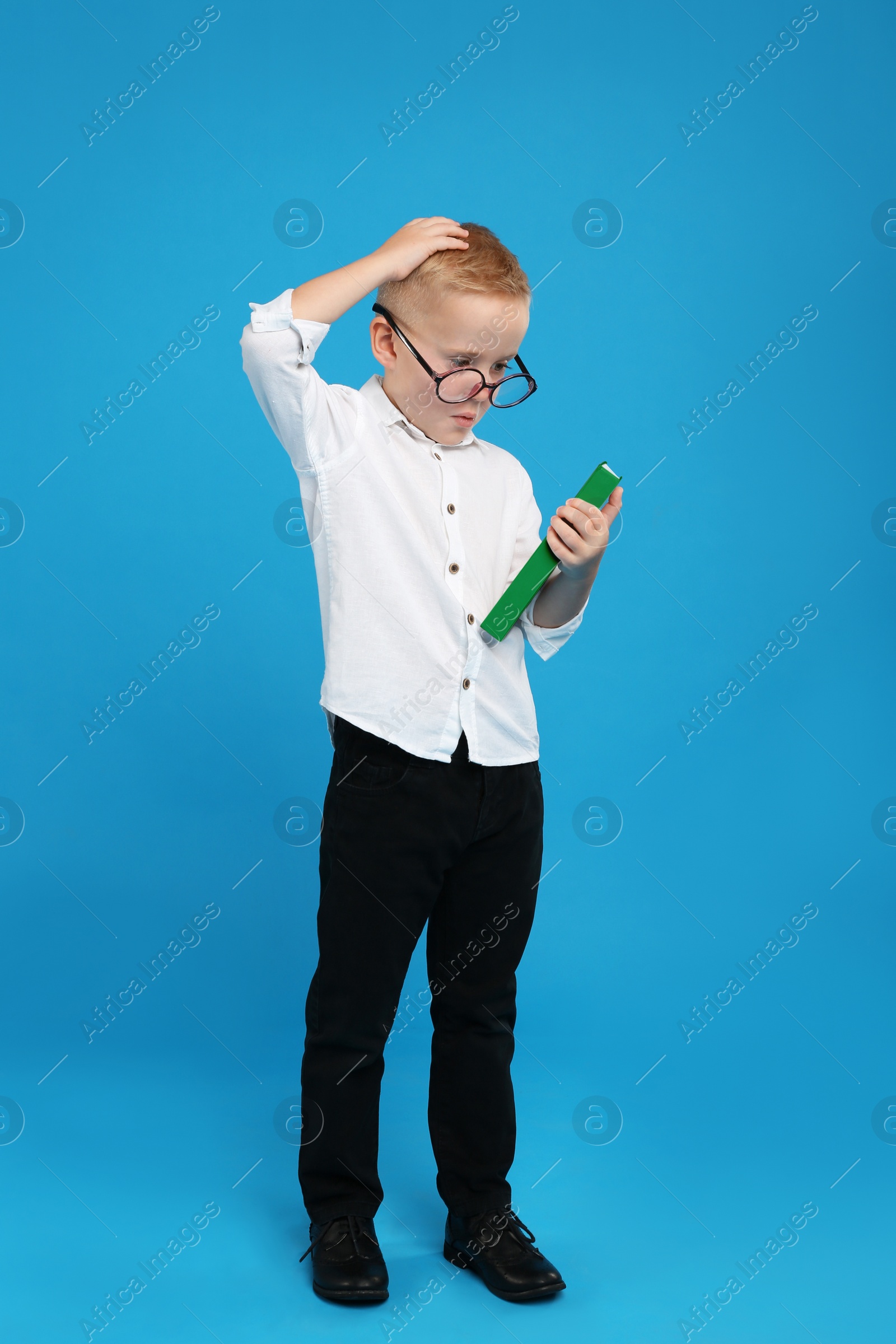 Photo of Full length portrait of cute little boy with book on light blue background