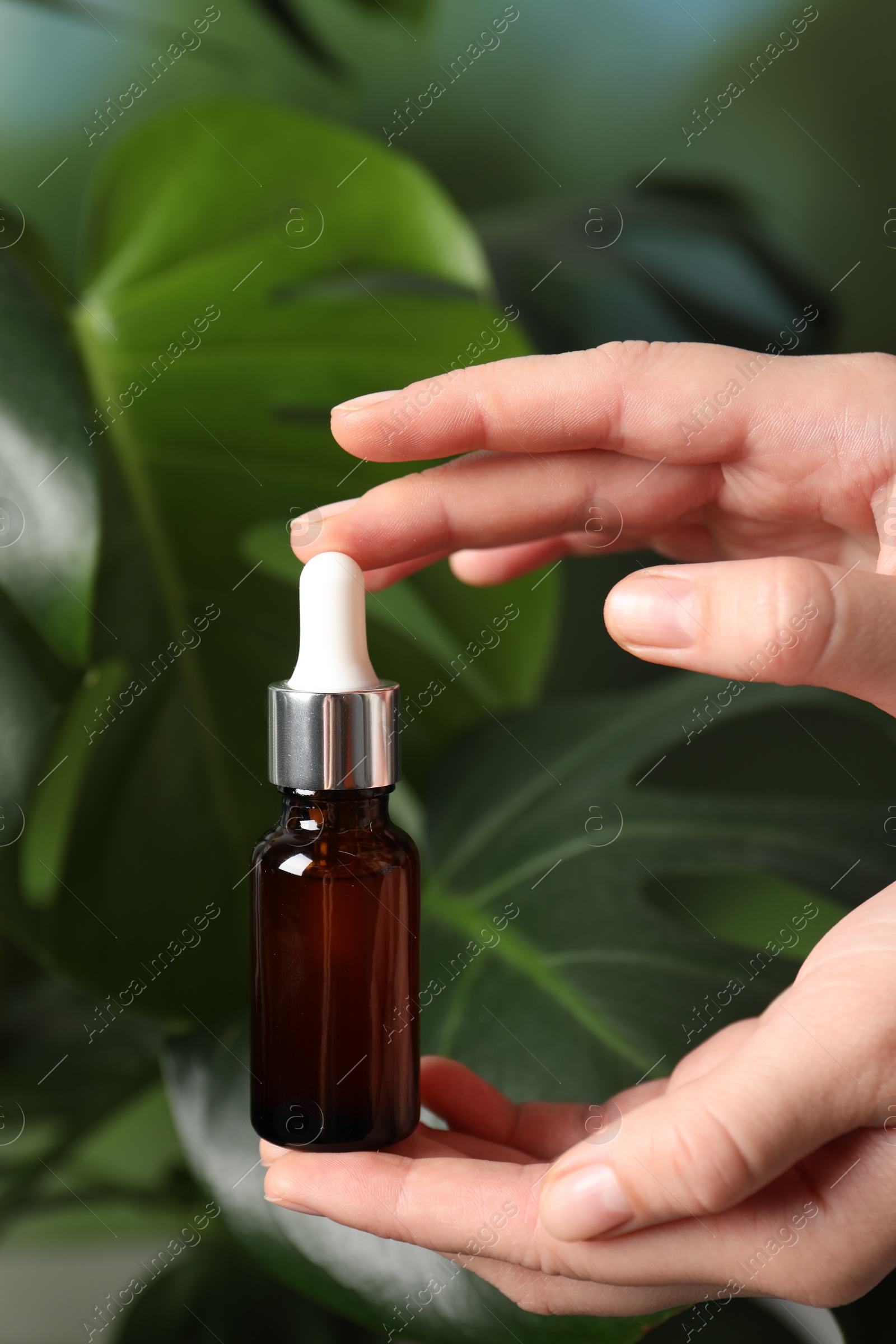 Photo of Woman with bottle of cosmetic serum on green background, closeup