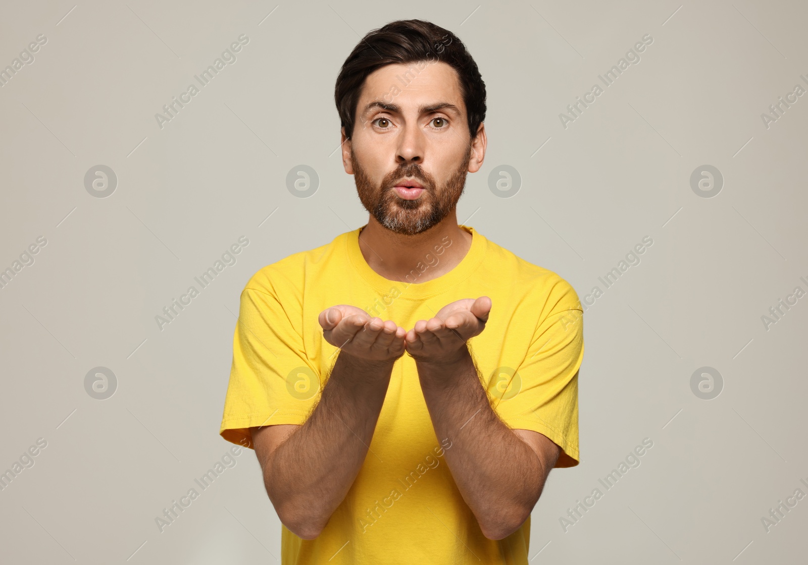 Photo of Handsome man blowing kiss on light grey background