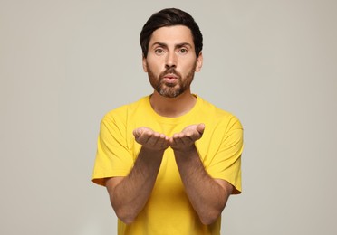 Photo of Handsome man blowing kiss on light grey background