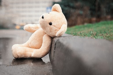 Lonely teddy bear in puddle on rainy day