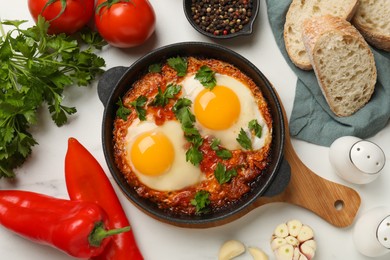 Flat lay composition with delicious shakshuka in frying pan on white table