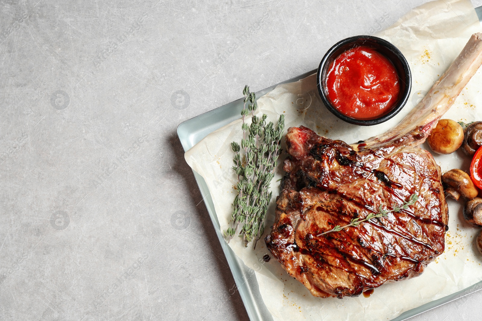 Photo of Delicious grilled ribeye with garnish on light table, top view. Space for text