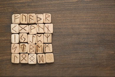 Photo of Runes with different symbols on wooden table, top view. Space for text