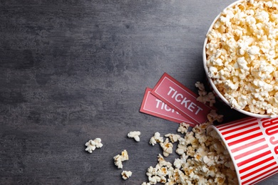 Photo of Popcorn and tickets on grey stone table, flat lay with space for text. Cinema snack