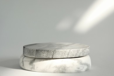 Photo of Presentation for product. Stone podium on light grey background. Space for text